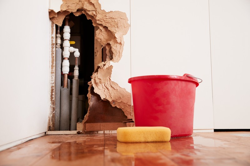 Damaged,Wall,,Exposed,Burst,Water,Pipes,,Sponge,And,Bucket